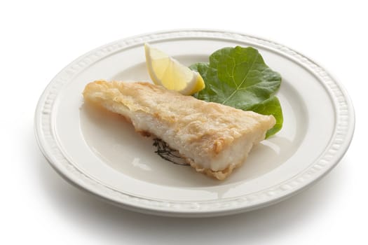 Fried fillet of pangasius with lettuce and lemon on the white plate