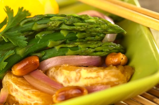 Green asparagus prepared in Thai-style with oranges, onions, cilantro and peanut in an orange-ginger sauce (Selective Focus, Focus on the asparagus head on the top)