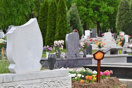 Tidied, well-kept cemetery with tombstones, ornamental plants and colourful flowers.