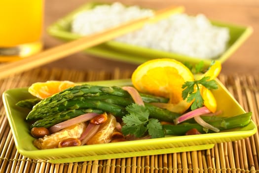 Green asparagus prepared in Thai-style with oranges, onions, cilantro and peanut in an orange-ginger sauce with rice in the back (Selective Focus, Focus on the asparagus head on the top)