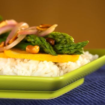 Green asparagus prepared in Thai-style with oranges, onions and peanut in an orange-ginger sauce served on rice (Selective Focus, Focus on the front of the orange slice, the two asparagus tips in the front and the peanut in the front)