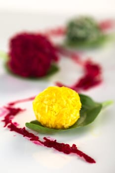 Pumpkin, beetroot and spinach coconut balls on basil leaves (Selective Focus, Focus on the front of the first ball) 