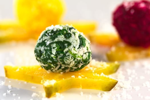 Spinach, beetroot and pumpkin coconut balls on a star fruit slice (Selective Focus, Focus on the front of the spinach coconut ball)
