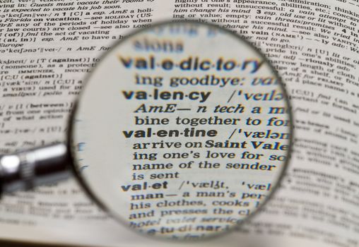 vaentine word in dictionary magnified by hand held magnifying glass