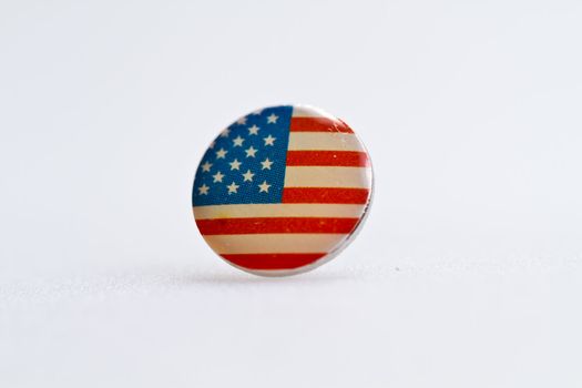 Usa flag symbol on metal thumbtack on white surface