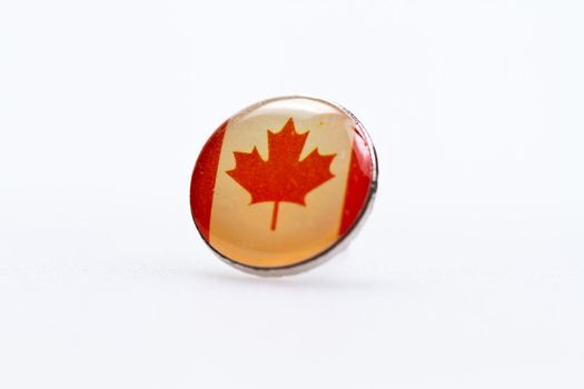 Canada flag symbl on thumbtack on white surface