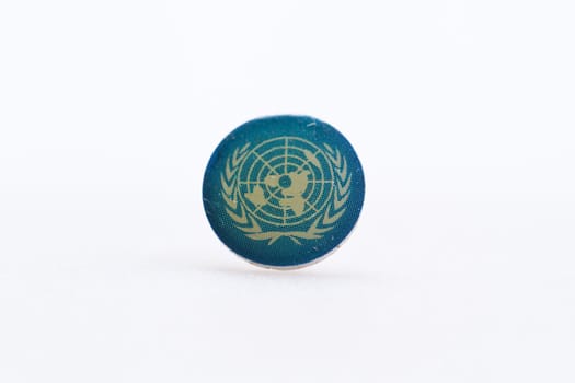 United Nation flag symbol on metal thumbtack on white surface