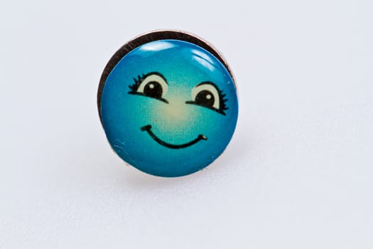 smiley character on metal thumbtack on white surface