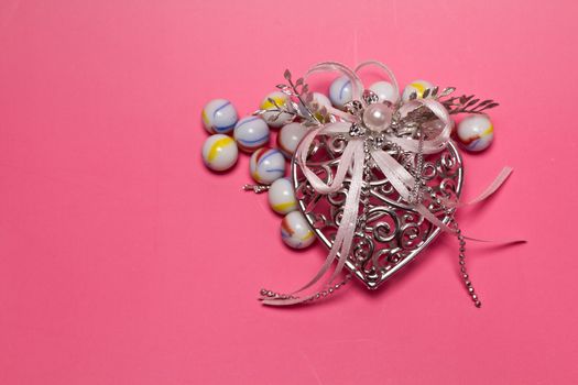 Silver metal heart with glass marbles on pinkish background for valentive use