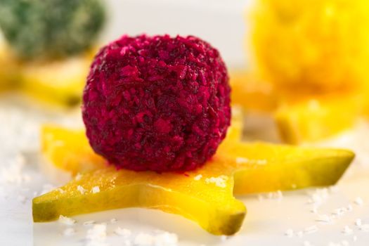 Beetroot, spinach and pumpkin coconut balls on a star fruit slice (Selective Focus, Focus on the front of the beetroot coconut ball)