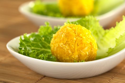 Pumpkin coconut ball on a lettuce leaf (Selective Focus, Focus on the front of the first pumpkin ball)