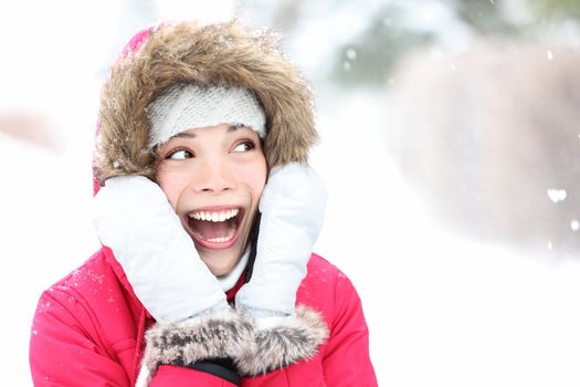 Excited winter woman looking to side smiling happy and joyful holding head. Beautiful mixed race asian cauasian girl playful in the snow.