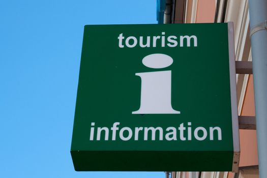 A green wall sign with Tourism