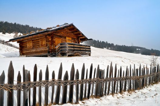 Old winter wood cottage with fence in Dolomiti Alps, Ortisei, italy.