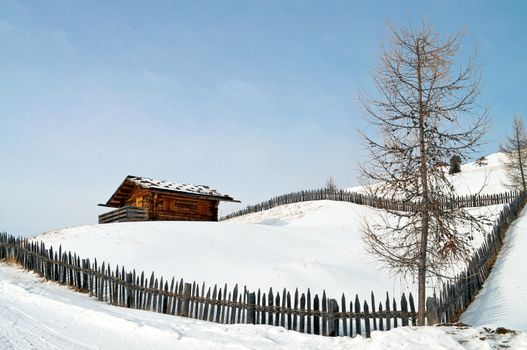 Old winter wood cottage with fence in Dolomiti Alps, Ortisei, italy.