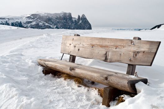 Isolated wooden bench on snow scape in dolomiti, Alps