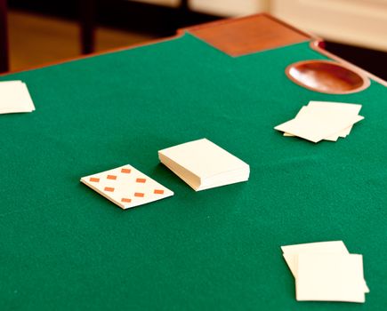 Deck of antique playing cards on green baize gaming table