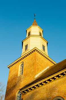 Warm sunlight at sunrise illuminates the brick tower of Bruton parish church in Williamsburg