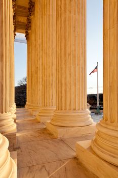 Late afternoon winter sun illuminates front of supreme court in Washington in winter with view of US flag