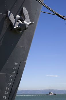 Vertical Composition of Moored Ship Bow and Anchor Tugboat Passing in Bay Underneath