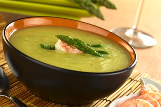 Cream of green asparagus with shrimp (Selective Focus, Focus on the shrimp and the upper asparagus head on the soup)