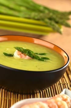 Cream of green asparagus with shrimp (Selective Focus, Focus on the shrimp and the upper asparagus head on the soup)