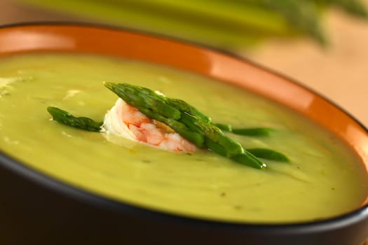Cream of green asparagus with shrimp (Selective Focus, Focus on the upper asparagus head on the soup)