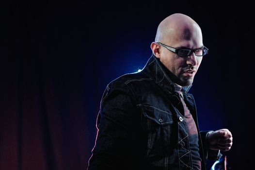 Man with glasses and in denim jacket. Studio-style portrait