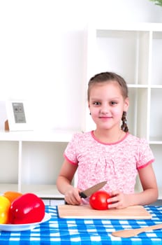 beautiful young girl cooking vegetables for a salad, working in kitchen