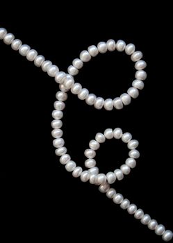 White pearls on the black silk as background 