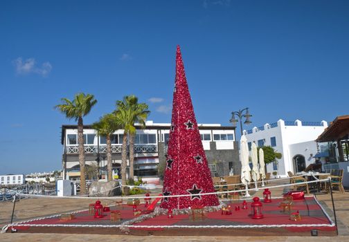 A Red Christmas Tree surrounded by presents and Red Lanterns in a town square