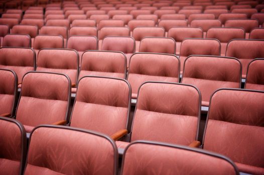 A horizontal shot of many rows of empty theatre seats