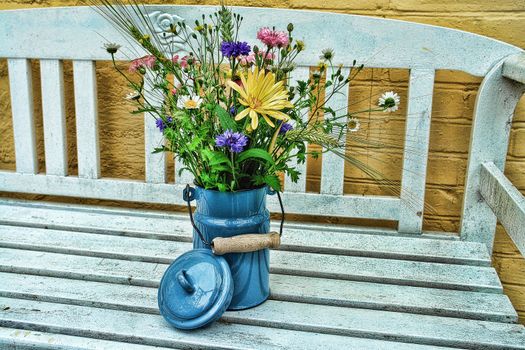 Beautiful spring summer flowers in a blue tin bucket on a garden bench digital art manipulation
