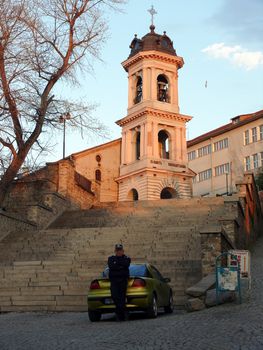 Plovdiv, Bulgaria - April 03, 2010: Policeman staying near the car in front of Saint Godmother Church. Plovdiv, Bulgaria