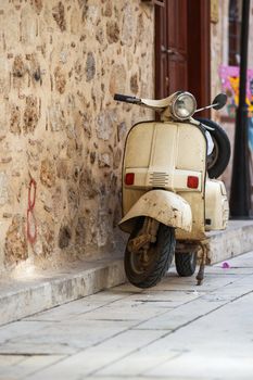 White vintage scooter parked in narrow old street of Antalya, Turkey