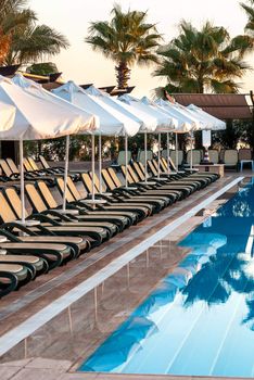 Early morning outdoor pool with sunbeds and umbrellas in luxury resort