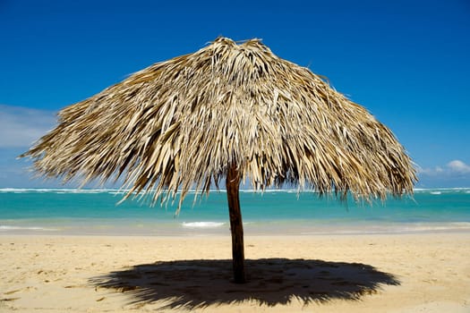 Parasol made out of palm leafs on beach.