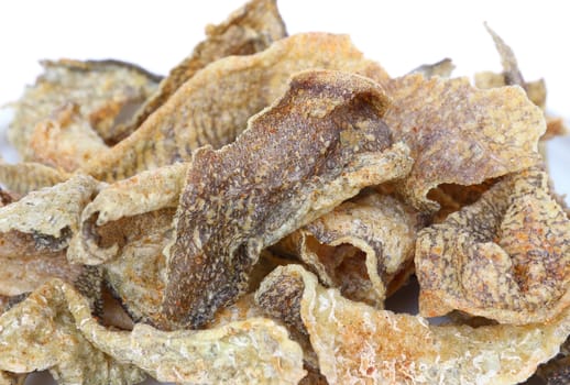 Crispy fried fish skin with spices on white background