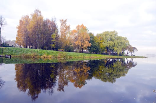 Beautiful view of lake and autumn trees on coast reflecting on water. Natural background.