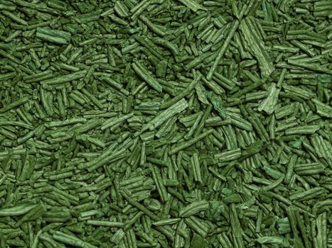Macro of green dry spirulina flakes used as food supplement rich of vitamins, antioxidants and minerals
