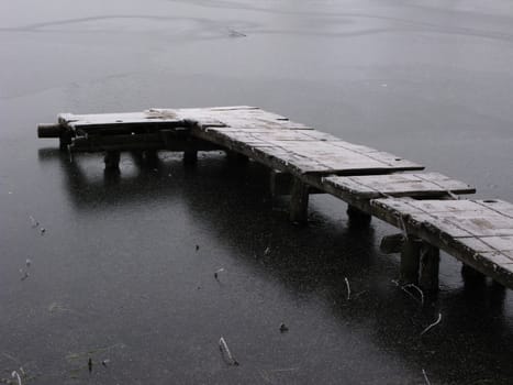 Frozen pond with planked footway, nasty weather