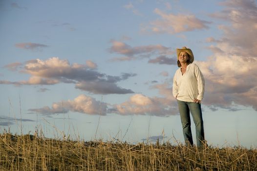 Wide angle shot of a western woman against a cloudy sky at dusk.