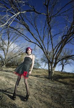 Punk fashion model in front of dead trees