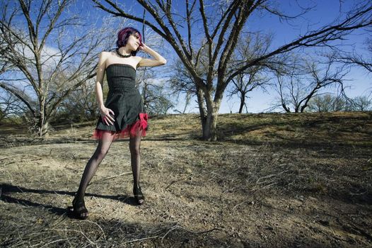 Punk fashion model in front of dead trees