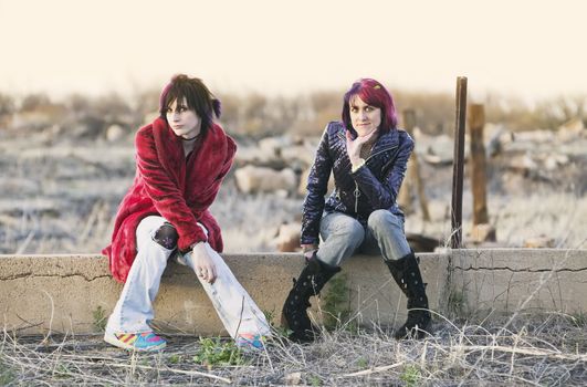 Two Fashion Girls Sitting on a Cement wall