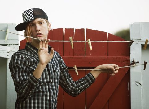 Portrait of a Teenage Boy Leaning on a Clothesline in front of a Fence