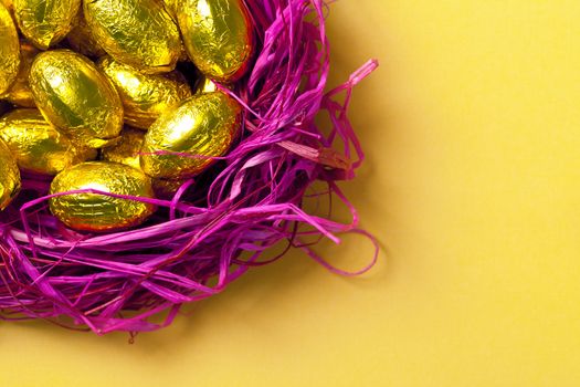 Chocolate easter eggs in pink nest. Holiday background. Top view. Macro shot