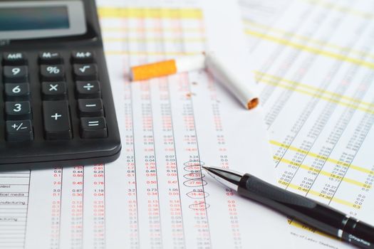 Calculator, pen with cigarette  on financial data.