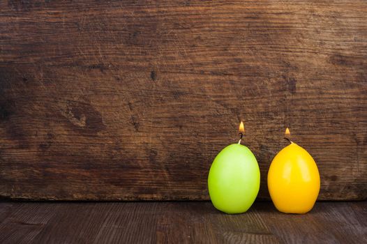 Candles in the form of eggs on the background of a wooden surface