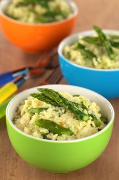 Green asparagus risotto in colorful bowls (Selective Focus, Focus on the two asparagus tips on the first risotto)